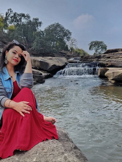 A red maxi dress paired with a denim jacket is a great choice for visiting a waterfall, combining style with practicality.