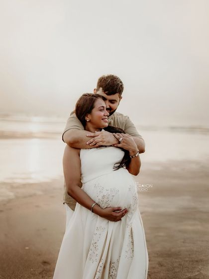 A warm hug from behind as they look out at the ocean. This pose beautifully frames the baby bump while capturing the couple's loving connection.