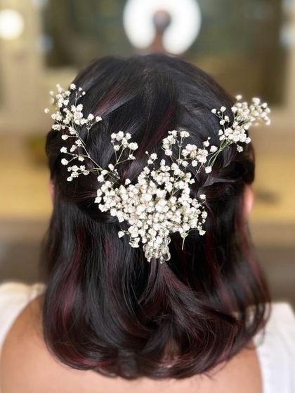 Baby's breath adds a delicate and ethereal touch to any hairstyle. This half-updo is beautifully decorated with a spray of the tiny white flowers, creating a soft, romantic look ideal for an engagement or daytime wedding event.
