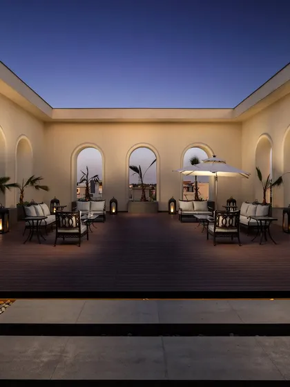The terrace of 'The Ivory Royale' is designed as a serene evening retreat. The classical arches frame the open sky, while soft, golden lighting creates an atmosphere of quiet luxury and timeless elegance, extending the home's regal character to its outdoor spaces.