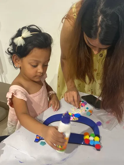 A mother helps her young daughter with a monogram craft. These activities are designed to be fun for both kids and parents, making for a perfect family outing.