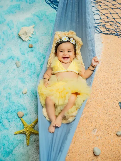 Another adorable shot from the hammock, showing off her happy expression. These relaxed poses are perfect for younger babies during their milestone photoshoots.