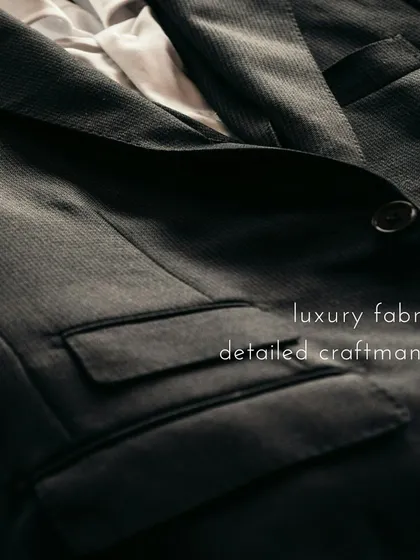 A detailed shot of a finished suit jacket, highlighting the texture of the luxury fabric and the precision of the craftsmanship in the pockets and lapel.
