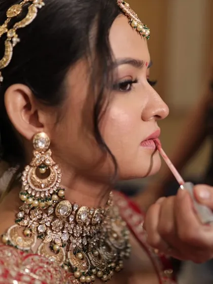 A behind-the-scenes look at the final touches on Krusha's bridal hairstyle. The elegant bun is adorned with a white rose and a beautiful matha patti.