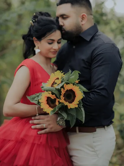 An artistic shot where the couple's embrace is partially hidden by a bouquet of sunflowers. This creative composition focuses on their connection while adding a touch of mystery and romance.
