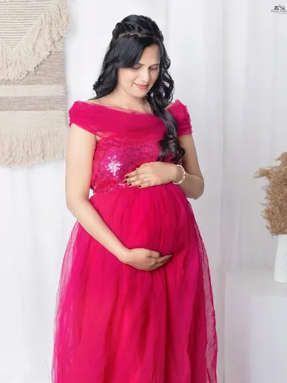Capturing the simple, loving gesture of a mother holding her belly. This pose is so natural and full of emotion. The off-shoulder magenta gown adds a touch of elegance to the portrait.