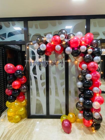 A vibrant birthday balloon arch in red, black, gold, and yellow. This setup is perfect for making a statement at the entrance of a party or as a main photo backdrop.