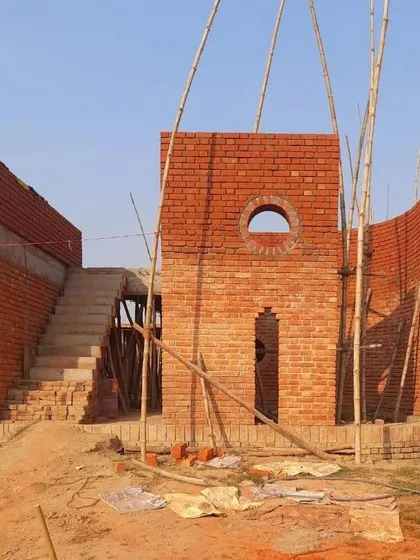 The form of the Ashadeep School, seen here rising from the earth, is a composition of simple, strong shapes. The circular window and open staircase were designed to be playful and engaging elements for the young students.