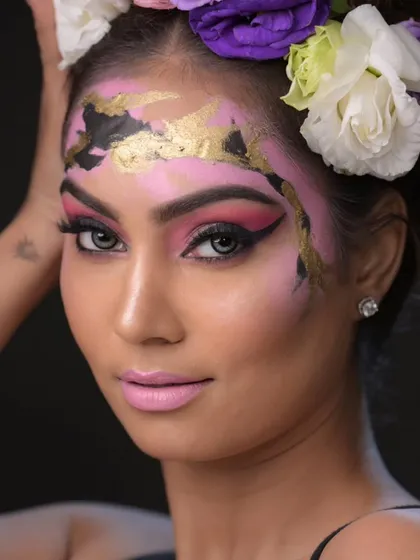 A direct portrait that highlights the beautiful contrast between the pink makeup, gold leaf, and the model's eyes.
