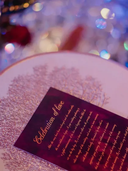 A personalized "Celebration of Love" card on an ornate plate, with the bokeh of blue and purple lights in the background, showcasing our attention to detail.