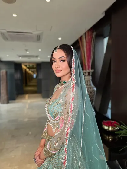 A side profile of the modern bride, showing how her soft open waves and dupatta draping create a dreamy and romantic silhouette.