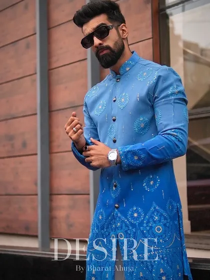 Adjusting the cuff on a piece designed for impact. The gradient blue and detailed patterns on this bandhgala kurta make it a modern classic for any wedding or festive event.