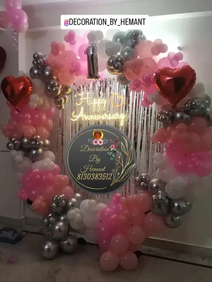 A 10th-anniversary celebration with a heart-shaped balloon ring. The pink, white, and silver chrome balloons create a romantic backdrop, complete with a neon sign and heart-shaped foil balloons.
