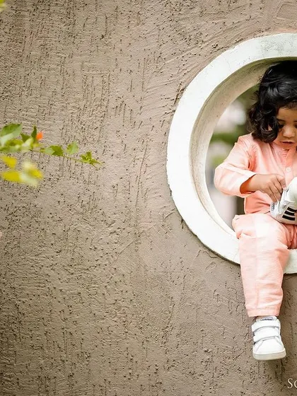 A child captured in a moment of quiet play, sitting in a circular window. This image is part of a series that shows how we can find beautiful, creative shots even in simple settings.