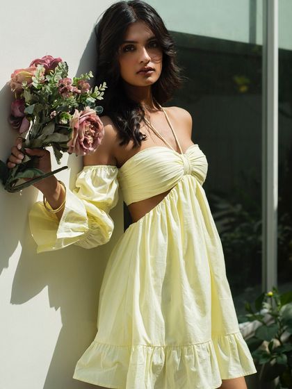 A soft and romantic summer fashion shot for Itgirl Love. The model holding a bouquet of flowers adds a touch of whimsy and highlights the delicate details of the off-shoulder dress.