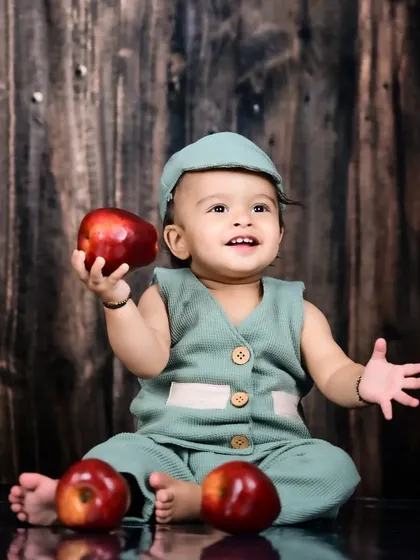 A happy baby boy holding an apple.