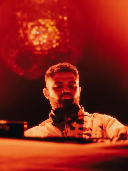 A close-up shot under intense red light, with a disco ball creating a classic club atmosphere in the background.
