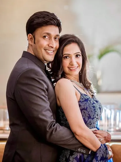 A polished and happy portrait of a couple at their engagement event. The soft lighting from the lamps in the background adds a warm and inviting ambiance.