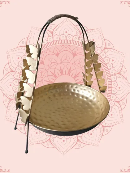 This unique golden platter with butterfly-adorned handles is a whimsical and stylish piece. The hammered texture of the bowl adds to its artisanal charm.