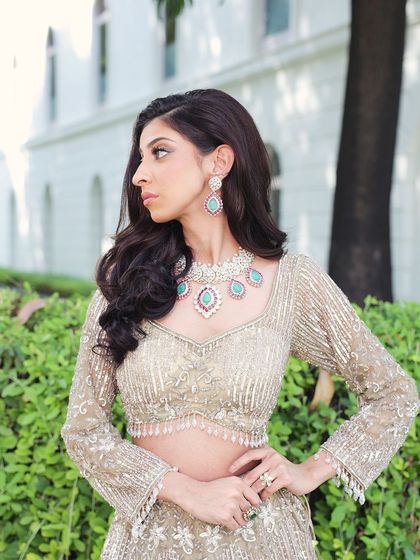 A side profile of a model in a sparkling gold lehenga, paired with beautiful turquoise jewelry. The contrast is stunning and perfect for a modern look.