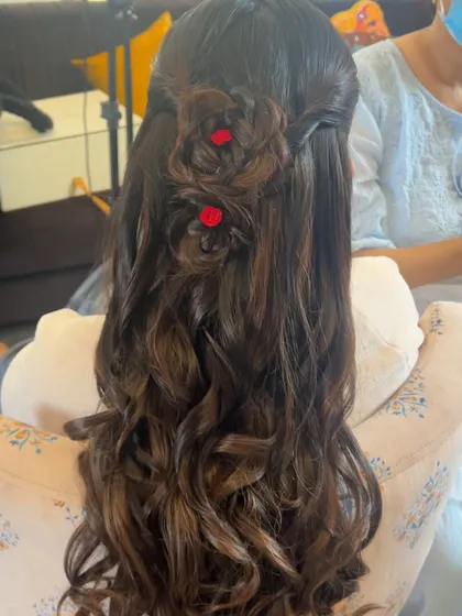 A unique half-updo with braided roses made from the hair itself, with tiny red flowers in the center.