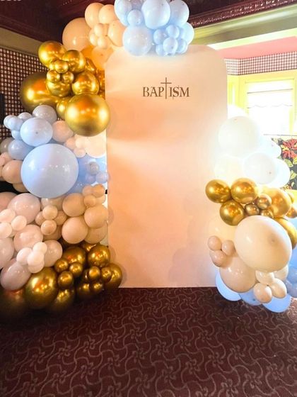 An elegant balloon decoration for a baptism ceremony. The setup uses white, gold, and pastel blue balloons to create a soft and serene atmosphere.