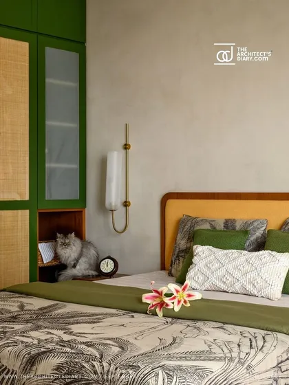 A serene bedroom featuring a custom bed with a mustard yellow headboard, set against a lime-washed wall and a green and rattan wardrobe.