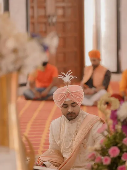 The groom sits in prayer during the ceremony, a moment of reverence and reflection captured with a soft, respectful focus.