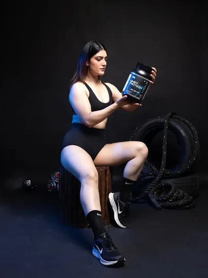 Here, the model holds the whey protein product up for inspection, drawing the viewer's eye directly to the container. This is a great shot for a product gallery, allowing customers to get a better sense of the packaging and size in a real-world context.