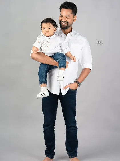 A father holds his son, a perfect picture of a proud dad. This classic portrait captures the quiet strength and love of a father.