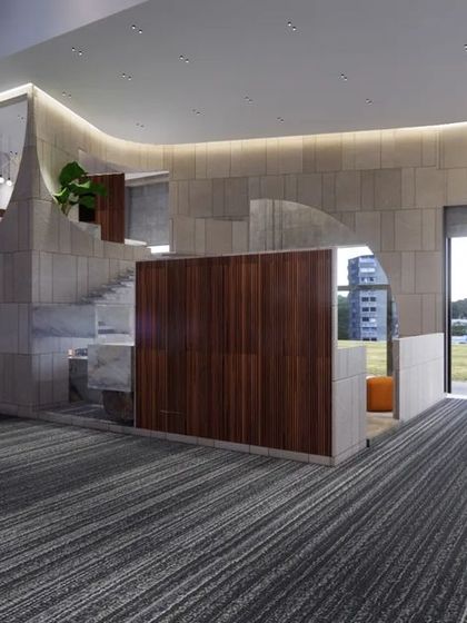 A wide view of the showroom's entrance area, highlighting the contrast between the striped carpet and the smooth, curved marble-clad structures. The open layout and large doorway connect the interior space with the surrounding landscape.