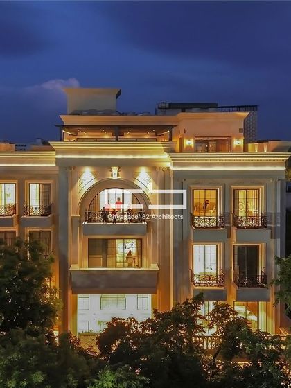 This facade blends modern design with classical accents, featuring ornate mouldings and clean lines for a striking visual balance. An elegant arched window introduces dynamism, while thoughtful lighting accentuates the architectural details at night.