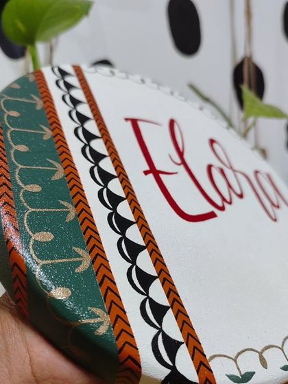 A side view of the "Elara" name plaque, highlighting the layered, hand-painted patterns in green, black, and gold that give the piece its depth.