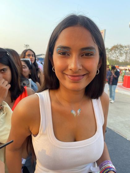 A client with a glittery eyeshadow look and a matching butterfly glitter tattoo on her collarbone.