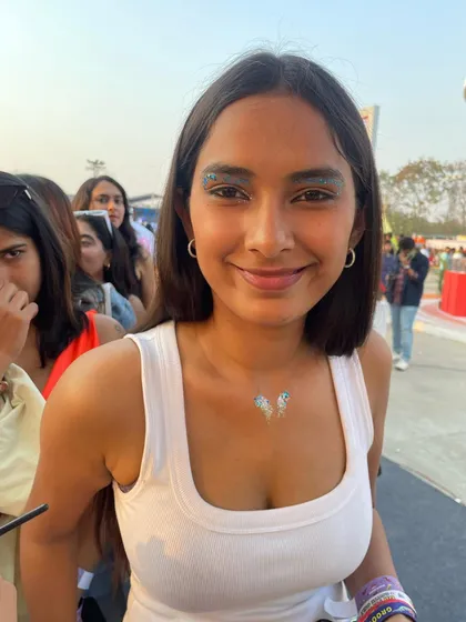 A client with a glittery eyeshadow look and a matching butterfly glitter tattoo on her collarbone.