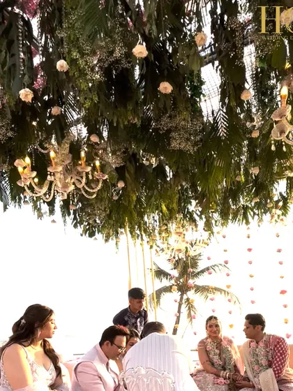 A beautiful moment under the lush floral canopy of the seaside mandap, with chandeliers adding a touch of elegance to the natural setting.