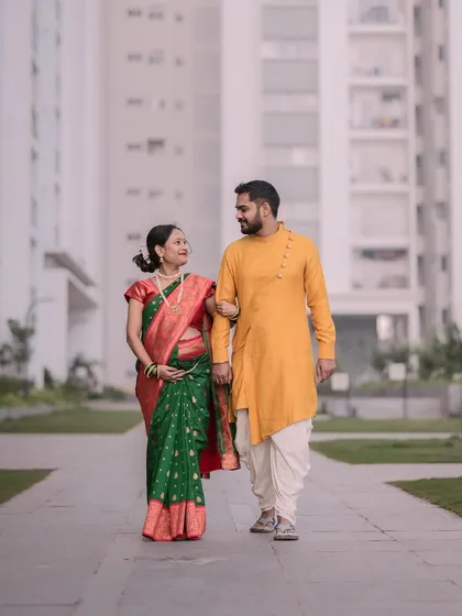 A full-length shot of the couple walking together during their maternity session. The modern building in the background gives it a contemporary urban feel.
