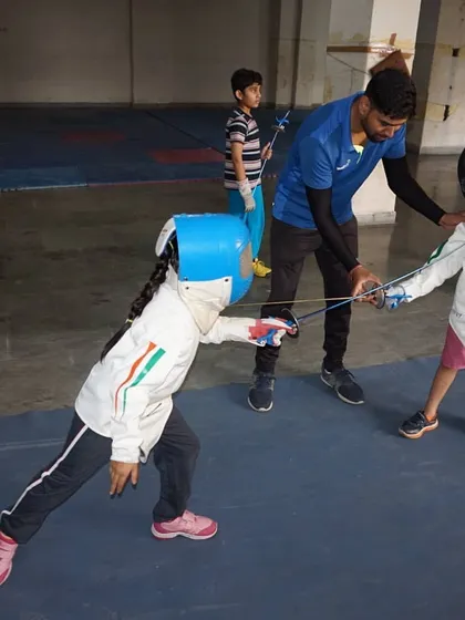 A coach carefully guides two very young fencers during their first practice bouts. We provide a safe and encouraging environment for beginners to learn the sport.