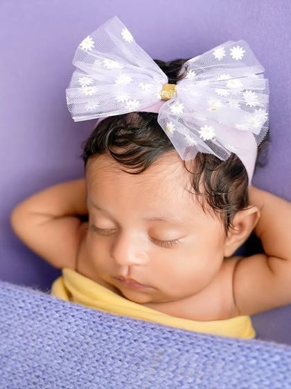 A relaxed newborn pose, with hands behind her head as if she's dreaming among the butterflies. It’s a playful and endearing moment captured forever.