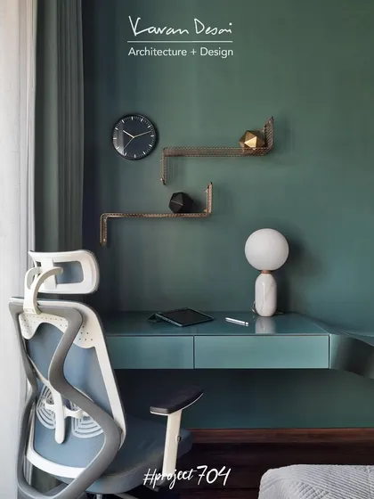 The study nook in the master bedroom features a sleek, modern desk and an ergonomic chair. The deep green wall color creates a calm and focused environment for work.