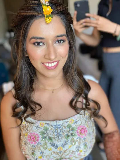 Getting this bride ready for her engagement. The makeup is fresh and subtle, with a pop of yellow floral detail in her hair for a festive touch.