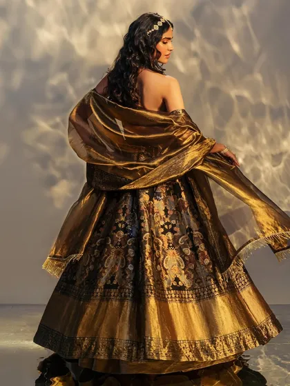 The back of a magnificent black and gold Benarasi lehenga. The sheer drama and beauty of the fabric make it a showstopper from every angle.
