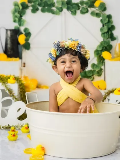 The pure excitement of turning one, captured in a single, joyful expression during her lemon-themed bath.