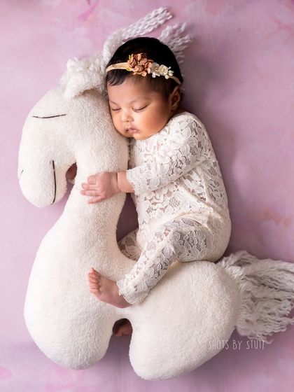 A whimsical shot of a baby riding a soft, fluffy horse prop. This is a fun and creative pose that adds a touch of magic to the gallery.