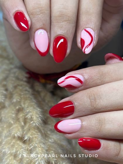 A playful yet chic design combining hot red and soft pink. The set features solid red nails, a red French tip, and an abstract swirl accent nail for a look that is both bold and classy.