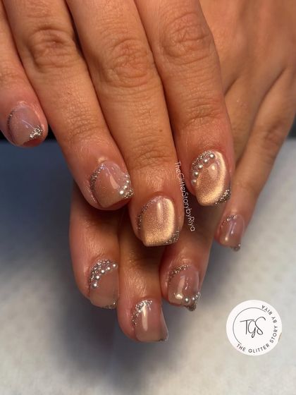 A delicate and sparkly design. This look features a neutral cat-eye base with a sprinkle of silver glitter and rhinestones near the cuticle for a touch of glamour.