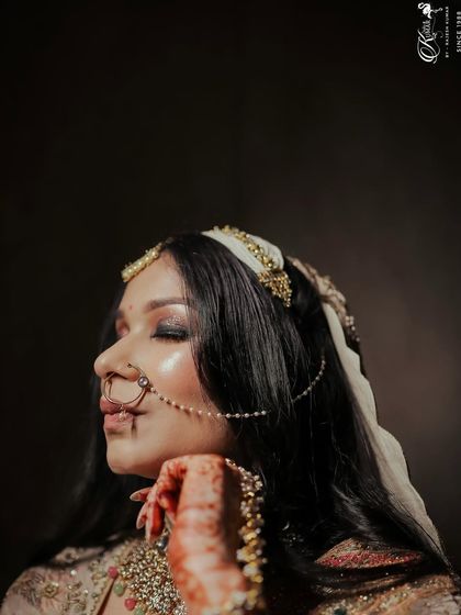 A profile shot of a bride, her eyes closed, showcasing her makeup and the side details of her hair and jewelry.