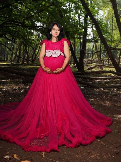 This magenta gown with a large bow detail and a dramatic train is perfect for a fairytale-themed maternity shoot in the forest.