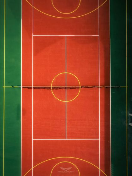 A perfectly symmetrical top-down shot of a tennis court, highlighting our eye for graphic compositions and detail in capturing sports amenities.
