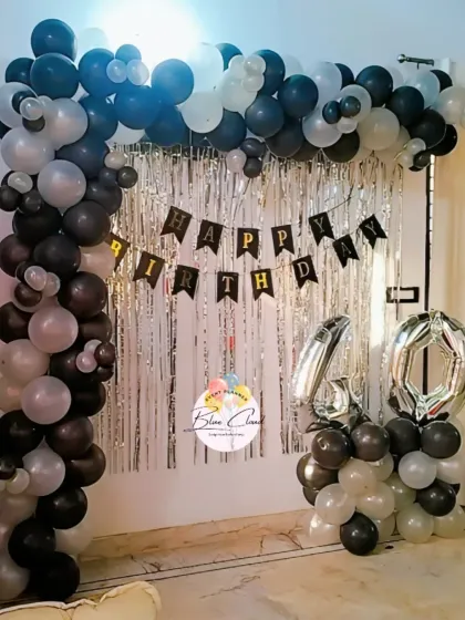 A stylish black, white, and silver balloon arch with a shimmer curtain for a 40th birthday.